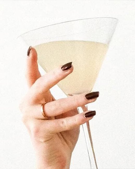 A manicured hand holding a cocktail