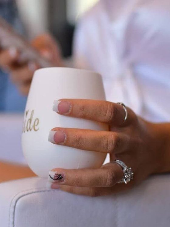 A guest with a fresh manicure holding a bride glass at a party booking